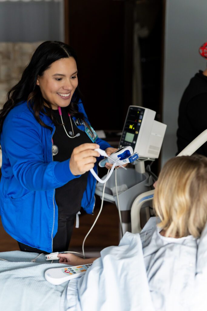nurse smiling while using monitoring device during patient care
