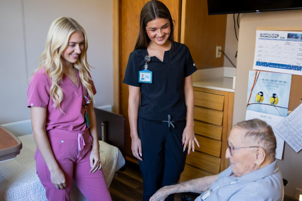 healthcare staff visiting elderly patient in room during care interaction