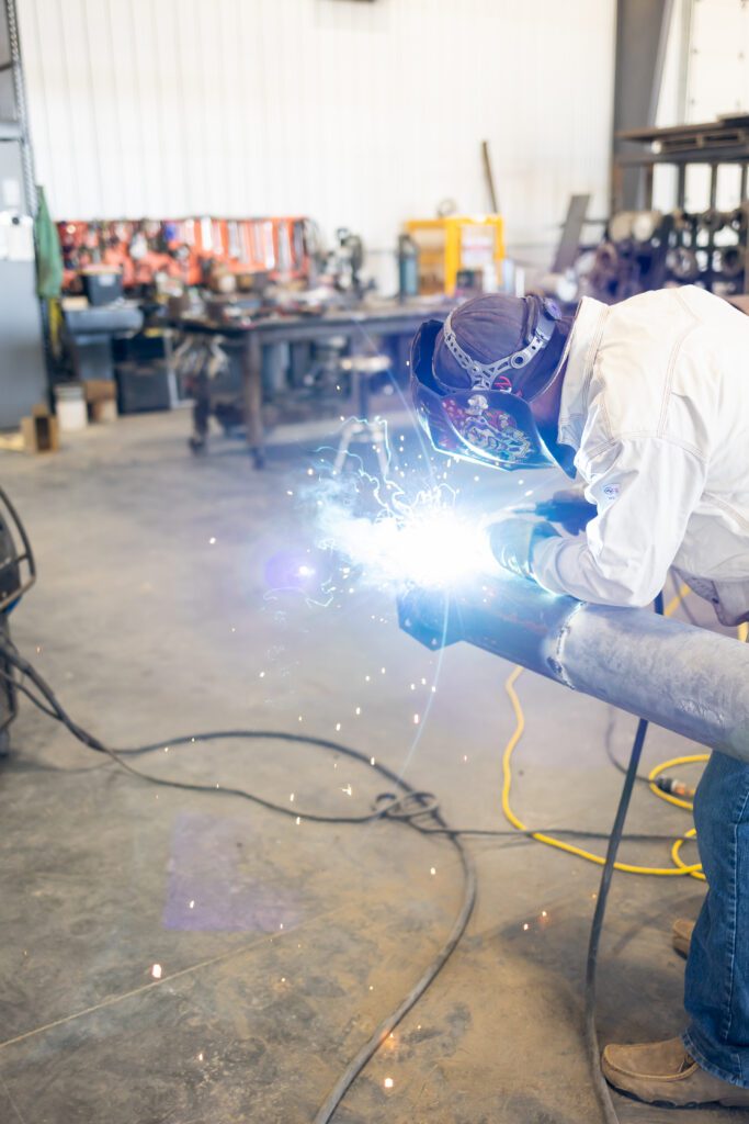 welder actively welding metal with sparks in workshop